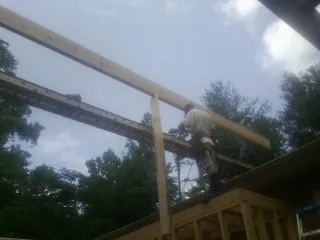 Carpenter setting a ridge beam over a new addition frame — Ice Dam Removal by Roofing Brothers in Denmark