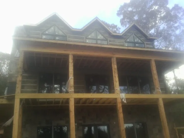 Dormers and porch framing on a large log home under construction — Roof Coating work by our crew in Denmark