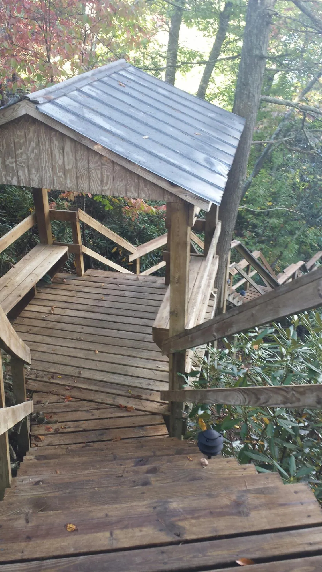 Metal roofed shelter over wooden steps on a wooded walkway — Skylight Repair & Installation work by our crew in Denmark